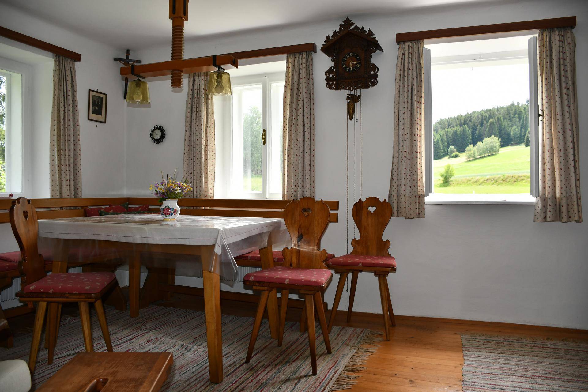Heller Essbereich mit Holzboden, traditionellen Stühlen und weitem Blick in die Natur.