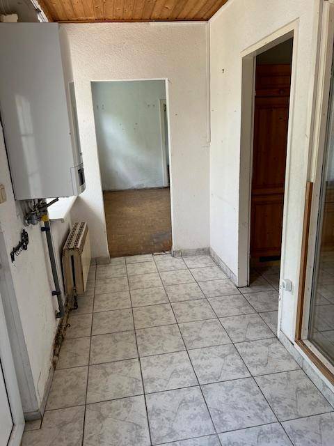 Flur mit Fliesenboden, Heizungsanlage an der Wand und Zugang zu weiteren Räumen.