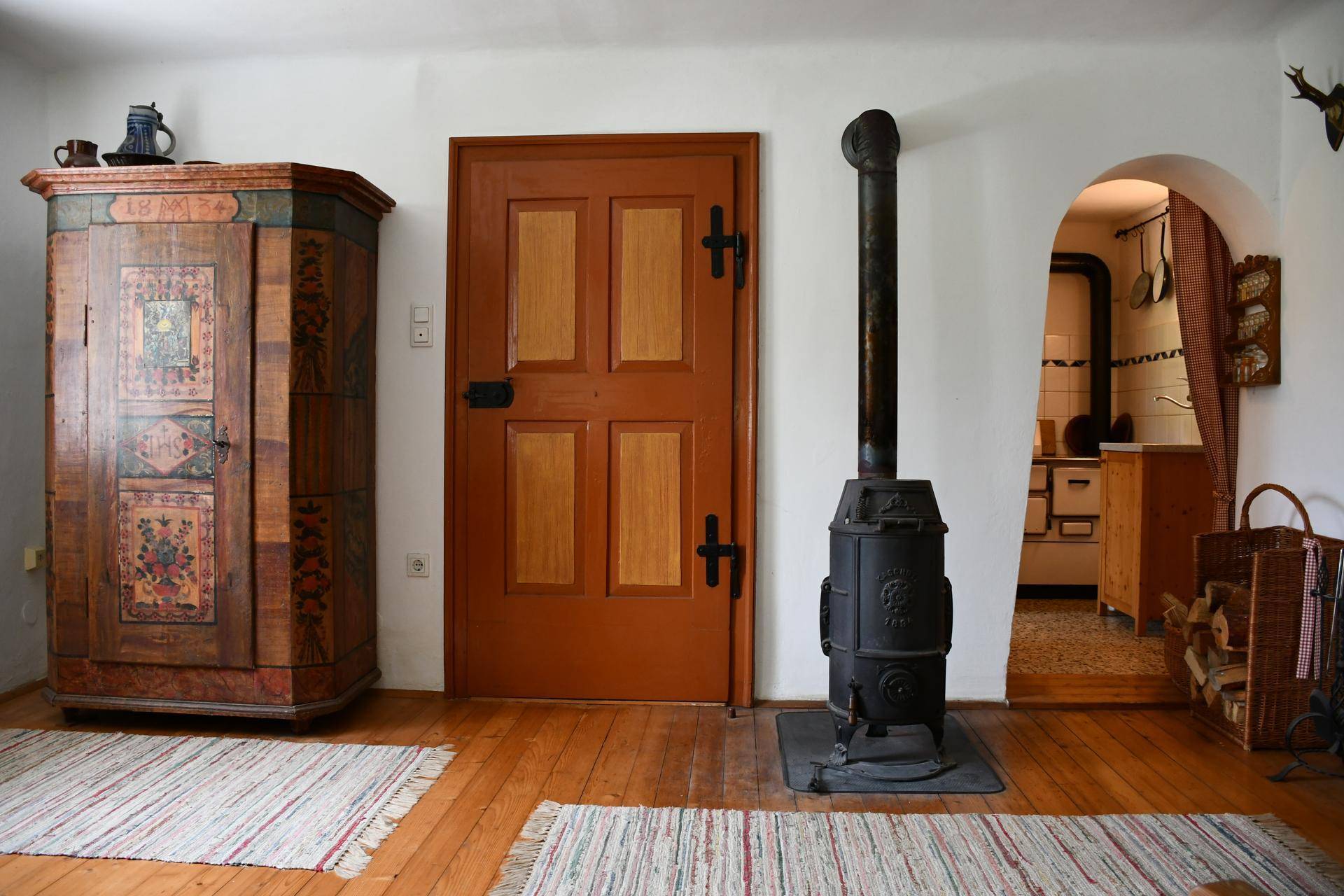 Wohnzimmer mit einem traditionellen Holzofen, antiken Möbeln und Holzboden.