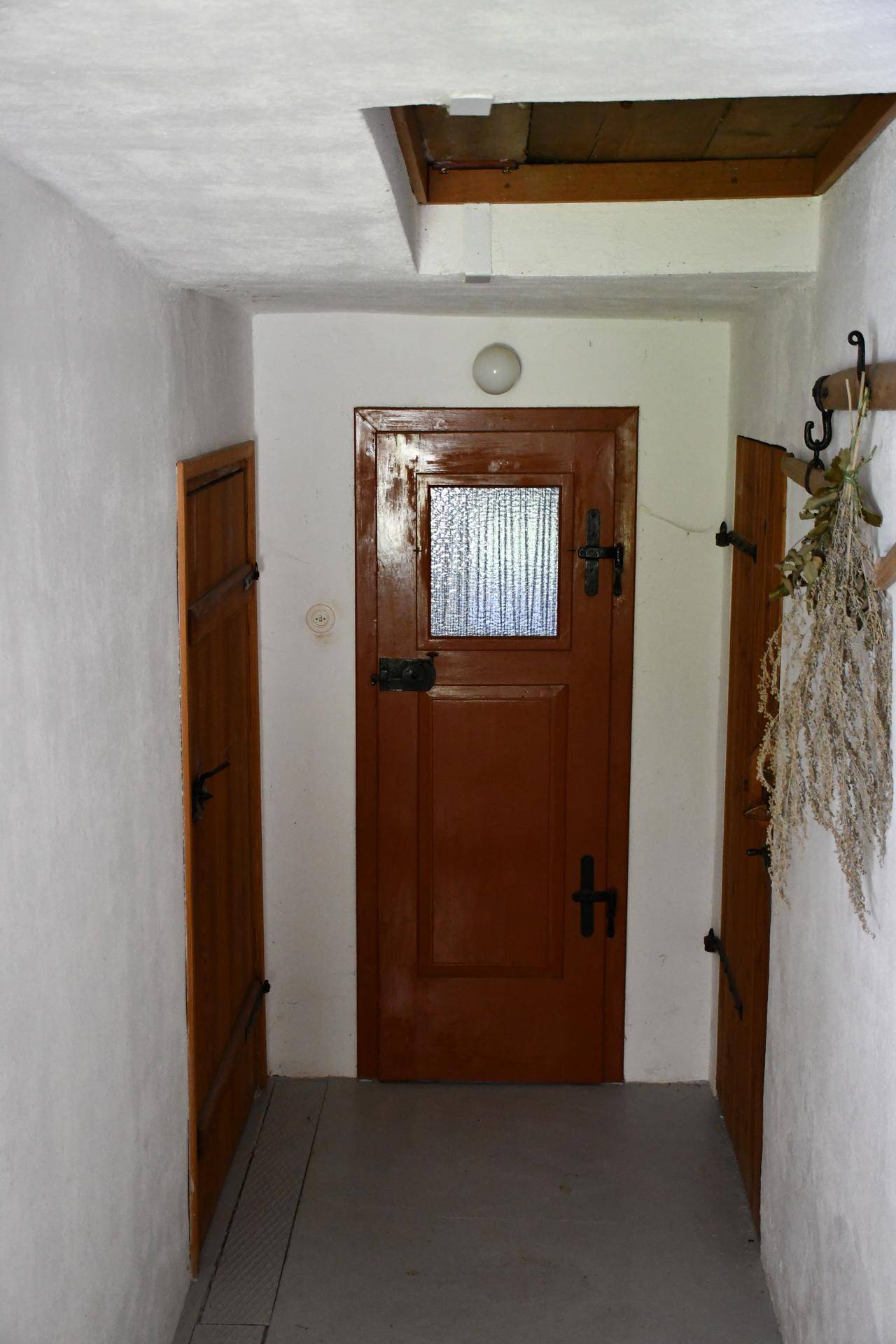 Heller Flur mit einer rustikalen Holztür, die ein kleines Fenster besitzt, und traditioneller Dekoration.