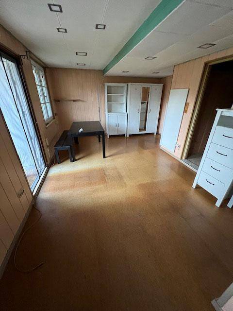 Geräumiger Innenraum mit Holzverkleidung, Laminatboden und einfacher Möblierung.