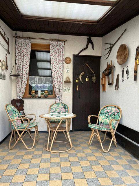 Wintergarten mit Korbmöbeln, gemusterten Fliesen und Fenster, ideal zum Entspannen.