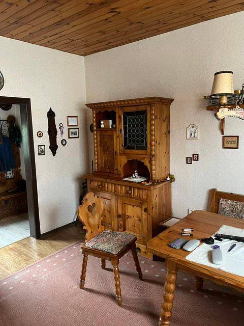 Rustikaler Essbereich mit Holzmöbeln, Holztäfelung an der Decke und Teppichboden.