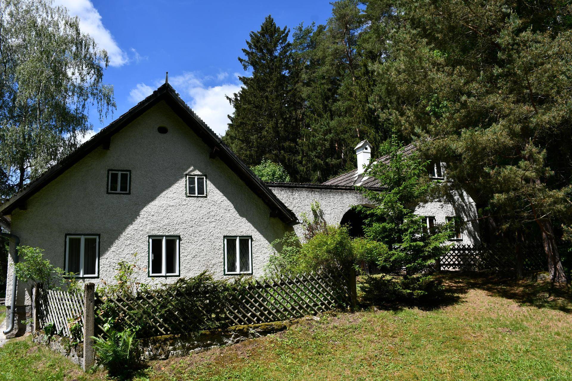 Landhaus mit weißer Fassade und traditioneller Architektur, umgeben von Bäumen und Natur.