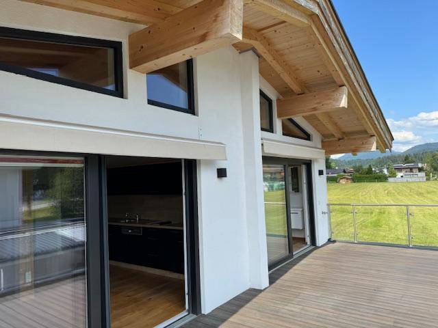 Moderne Architektur mit großen Glasfronten und einem weitläufigen Balkonbereich mit Bergblick.