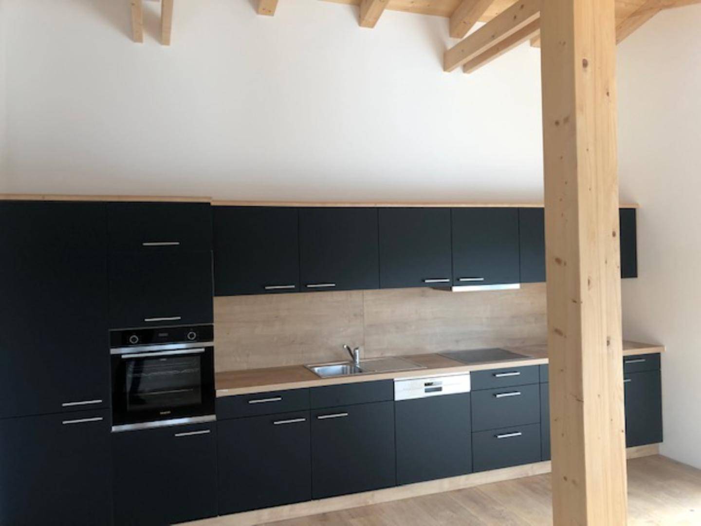 Moderne Einbauküche in Schwarz mit Holzdetails und integrierten Geräten.