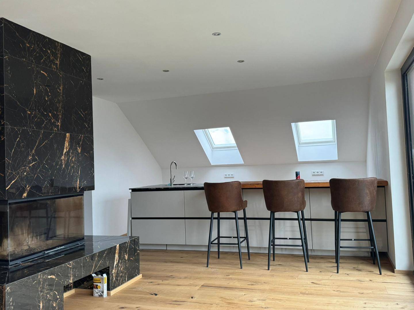 Moderne Küchenzeile mit Bartheke, Marmorkamin und Dachfenstern für viel Tageslicht.