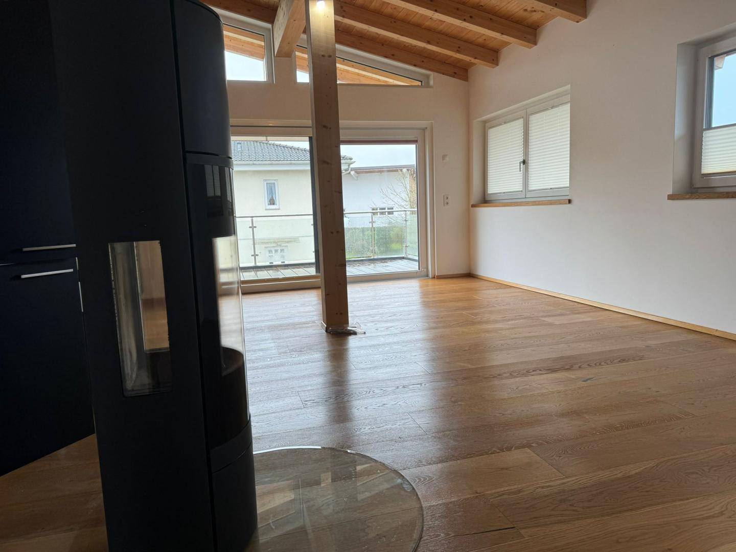 Heller Wohnbereich mit Kaminofen, Holzboden und Zugang zu einem Balkon.