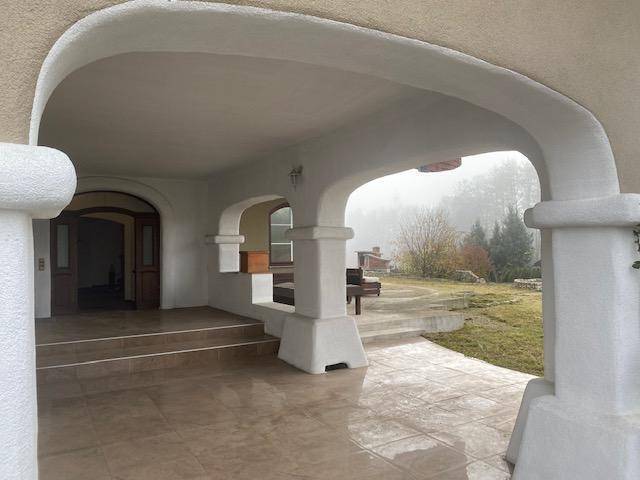 Einladender überdachter Eingangsbereich mit Bögen und Blick auf den nebligen Gartenbereich.