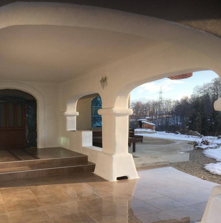 Überdachter Eingangsbereich mit Fliesenboden und Rundbögen, der in eine verschneite Landschaft blickt.