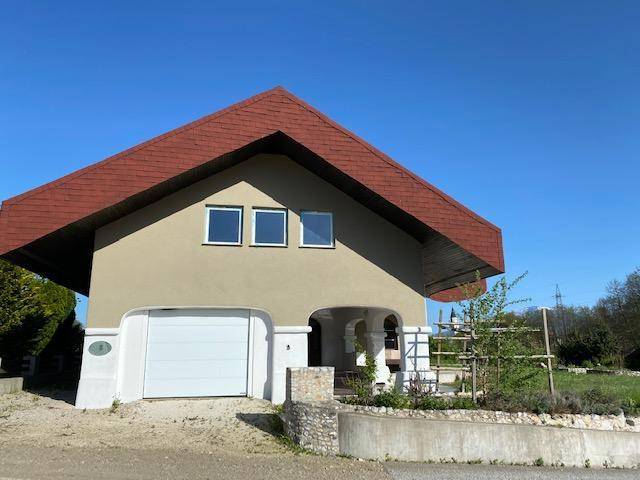 Vorderansicht des Hauses mit Garage und dem markanten roten Dach unter strahlend blauem Himmel.