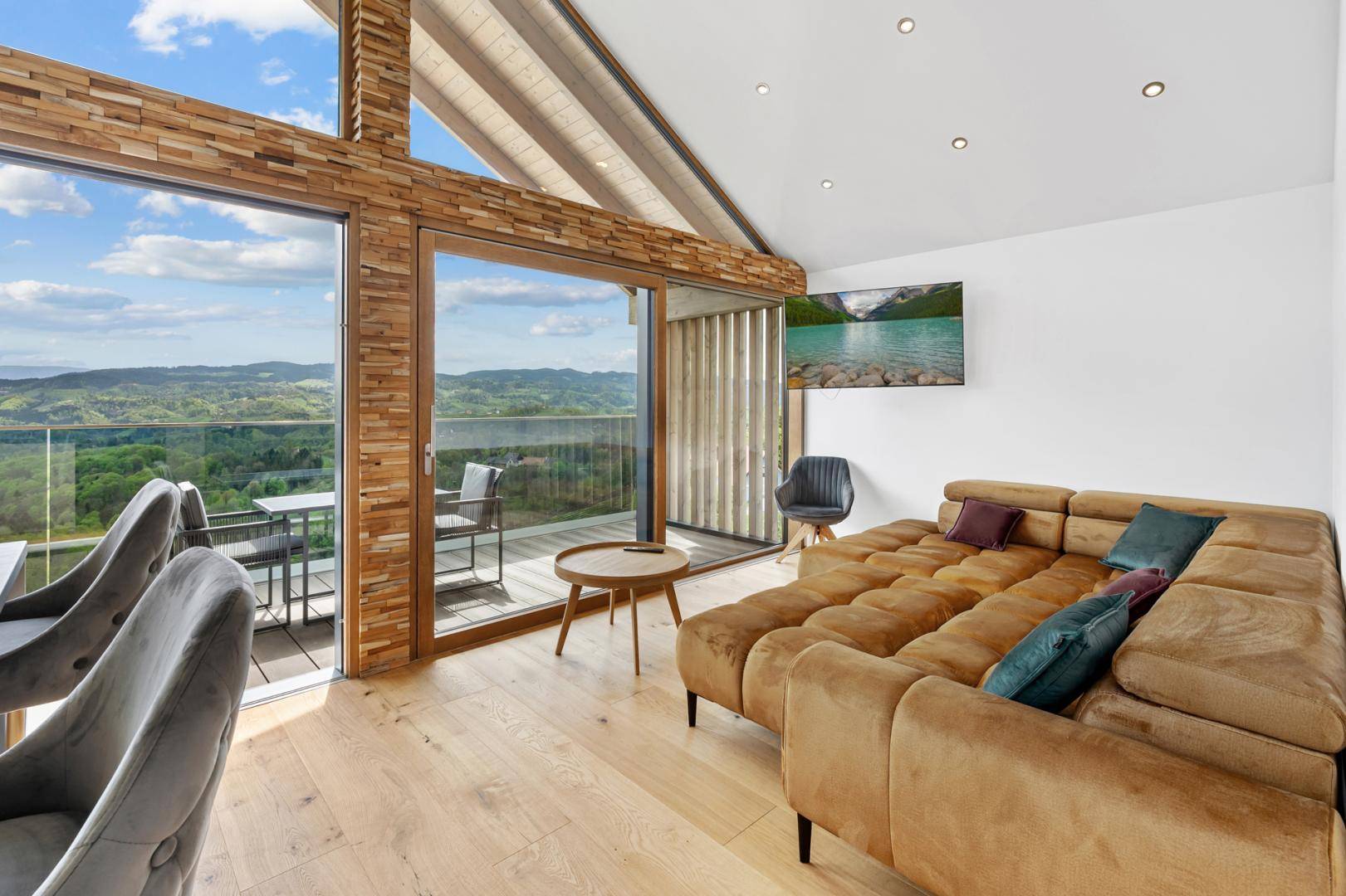 Geräumiges Wohnzimmer mit großem Sofa und bodentiefen Fenstern, die einen atemberaubenden Blick auf die Landschaft bieten.
