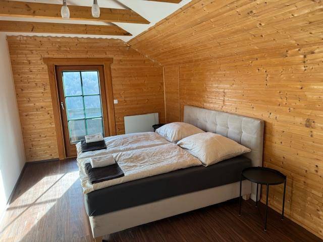 Schlafzimmer mit Holztäfelung, Doppelbett und Zugang zu einem Balkon oder Terrasse.