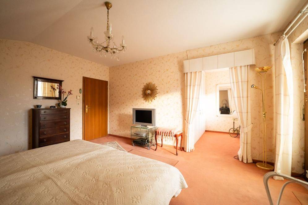 Gemütliches Schlafzimmer mit Teppichboden, Doppelbett, klassischer Einrichtung und viel Tageslicht.