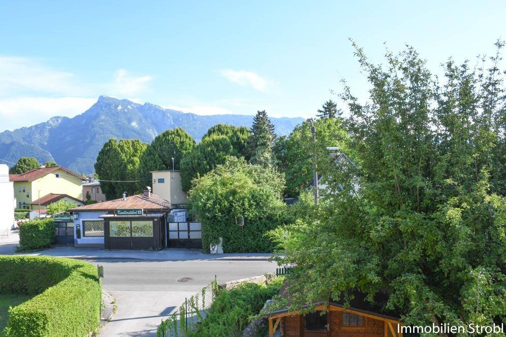 Panoramablick auf die Berge und grüne Umgebung mit einer Straße im Vordergrund.