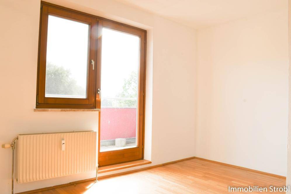 Helles Zimmer mit Holzboden, großem Fenster und Heizkörper, ideal als Schlaf- oder Kinderzimmer.