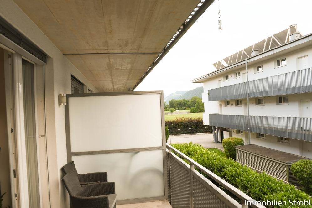 Balkon mit Sitzgelegenheiten und Blick auf die umliegenden Gebäude und Grünflächen.