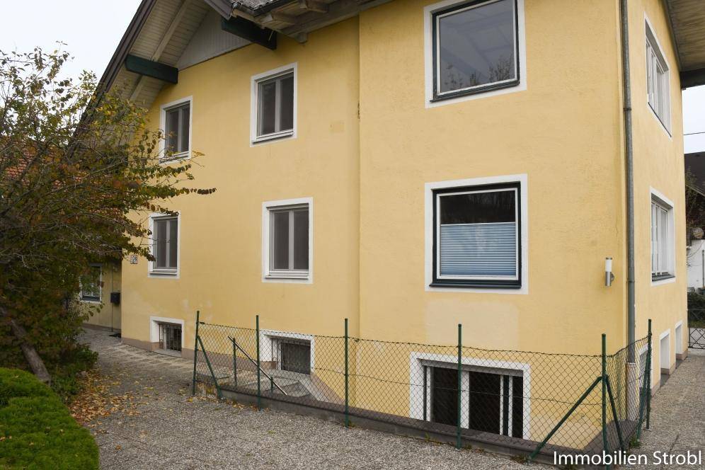 Seitenansicht des gelben Hauses mit Zugang zum Keller und einem gepflasterten Weg.