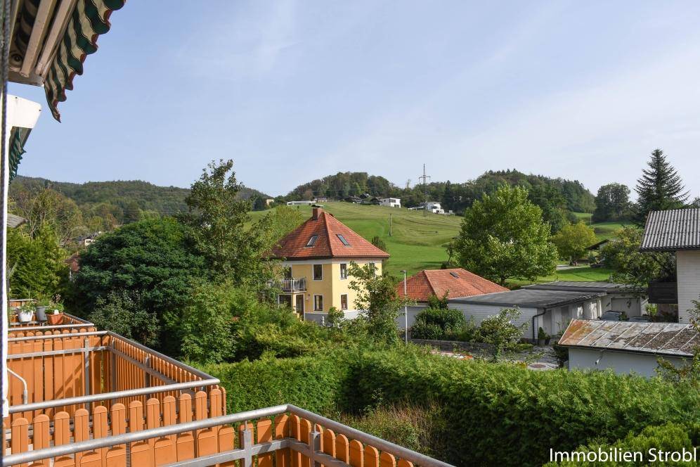 Balkon mit weitem Blick über grüne Hügel und ländliche Bebauung.