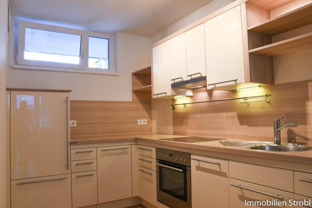 Moderne Einbauküche mit hellen Fronten, Holzoptik-Arbeitsplatten und integrierten Geräten.