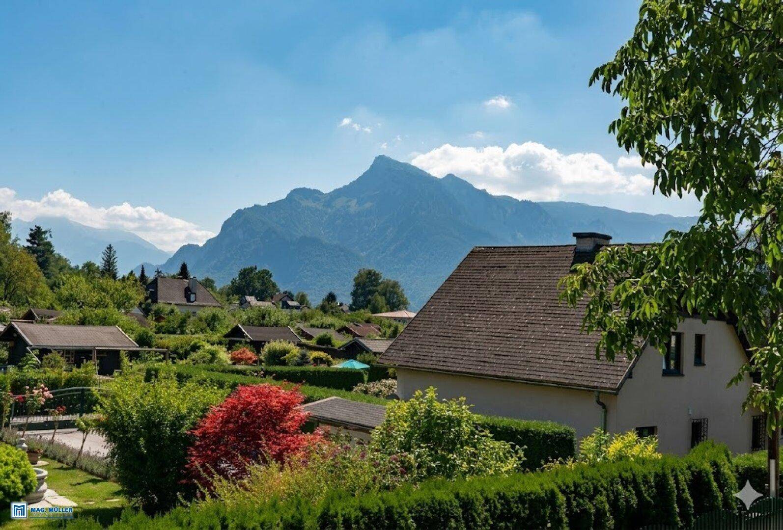 Idyllischer Ausblick auf Häuser, üppiges Grün und eine beeindruckende Bergkulisse unter blauem Himmel.
