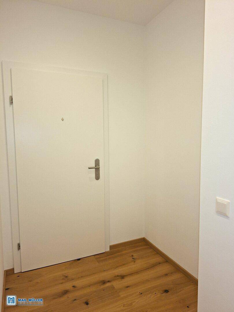Weiße Eingangstür in einem hellen Flur mit Holzboden.