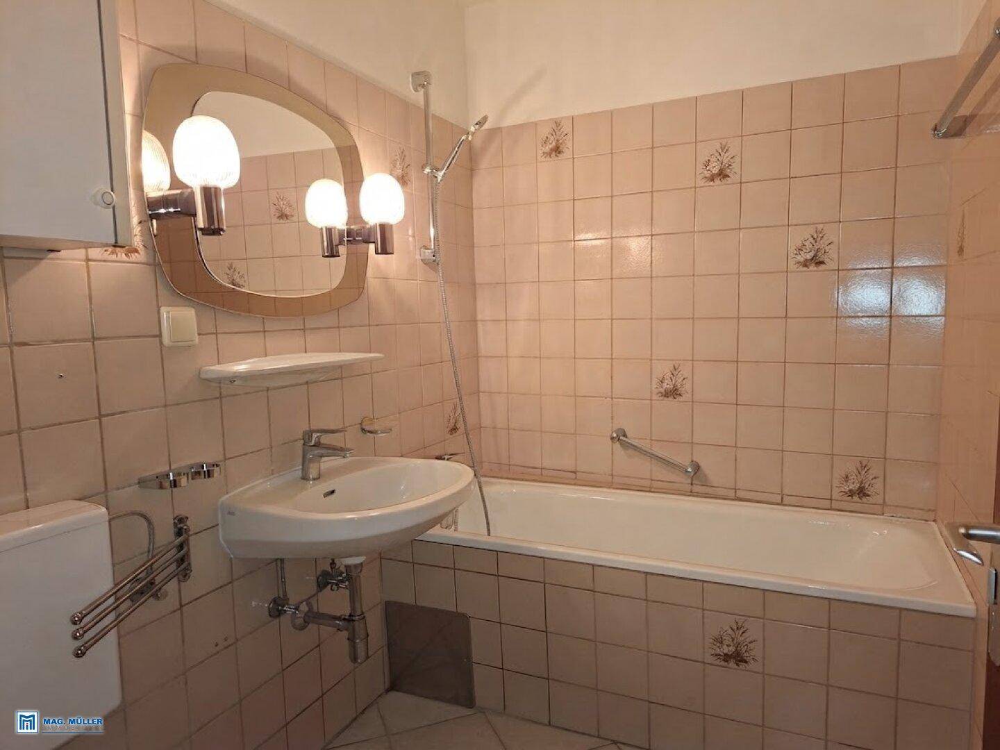 Badezimmer mit rosa Fliesen, Badewanne, Waschbecken und Spiegel.