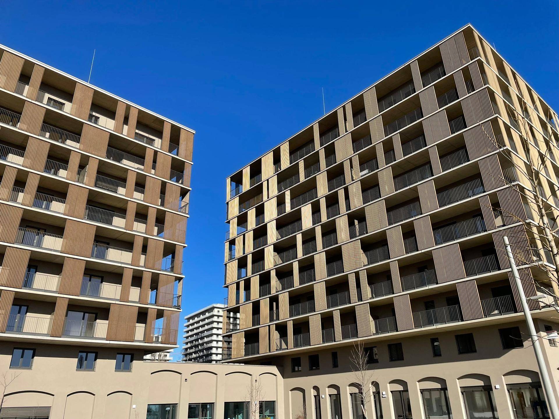 Moderne Wohngebäude mit vielen Balkonen und einer ansprechenden Fassadengestaltung unter blauem Himmel.