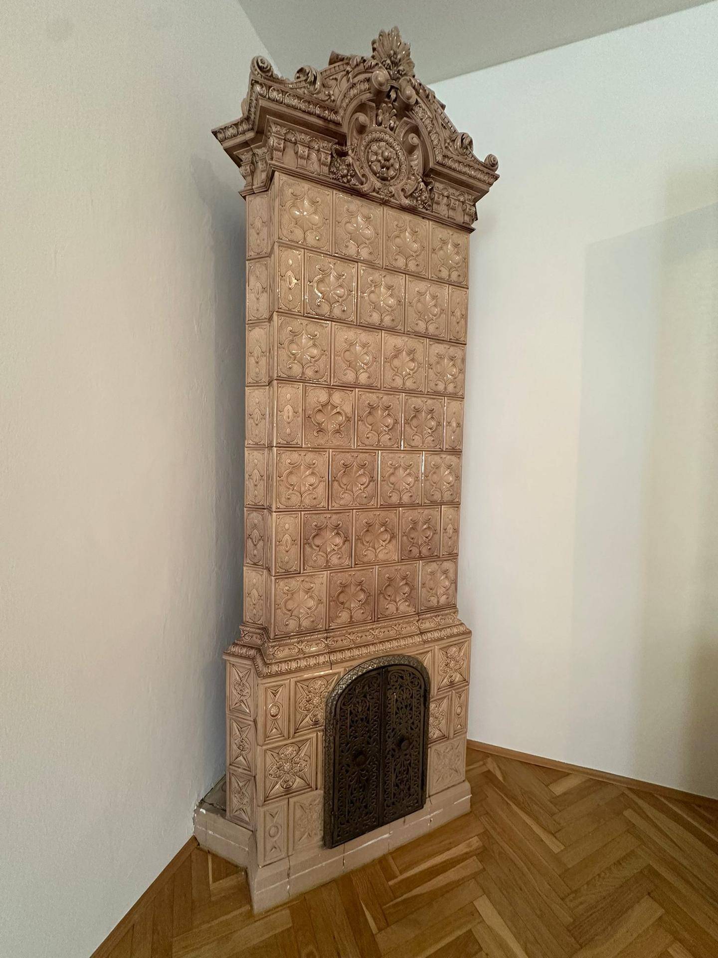 Historischer Kachelofen mit aufwendigen Verzierungen und traditionellem Design in einem Wohnraum.