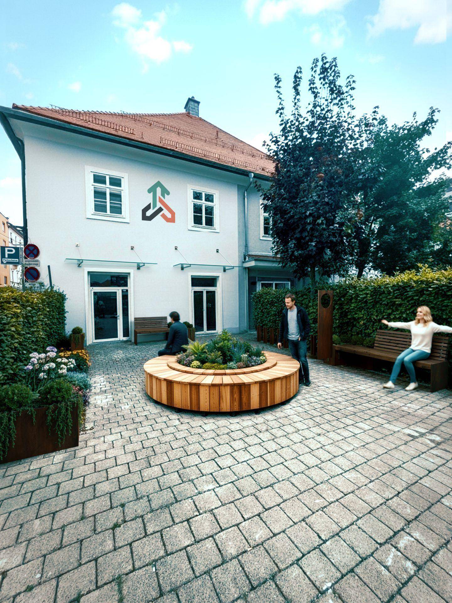 Außenansicht eines Gebäudes mit gepflastertem Vorplatz, Holzbänken und begrünten Pflanzbeeten.