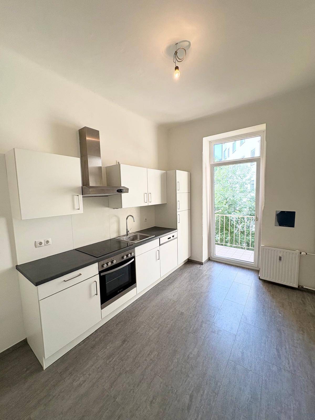 Helle Küche mit moderner Ausstattung und direktem Zugang zu einem kleinen Balkon.