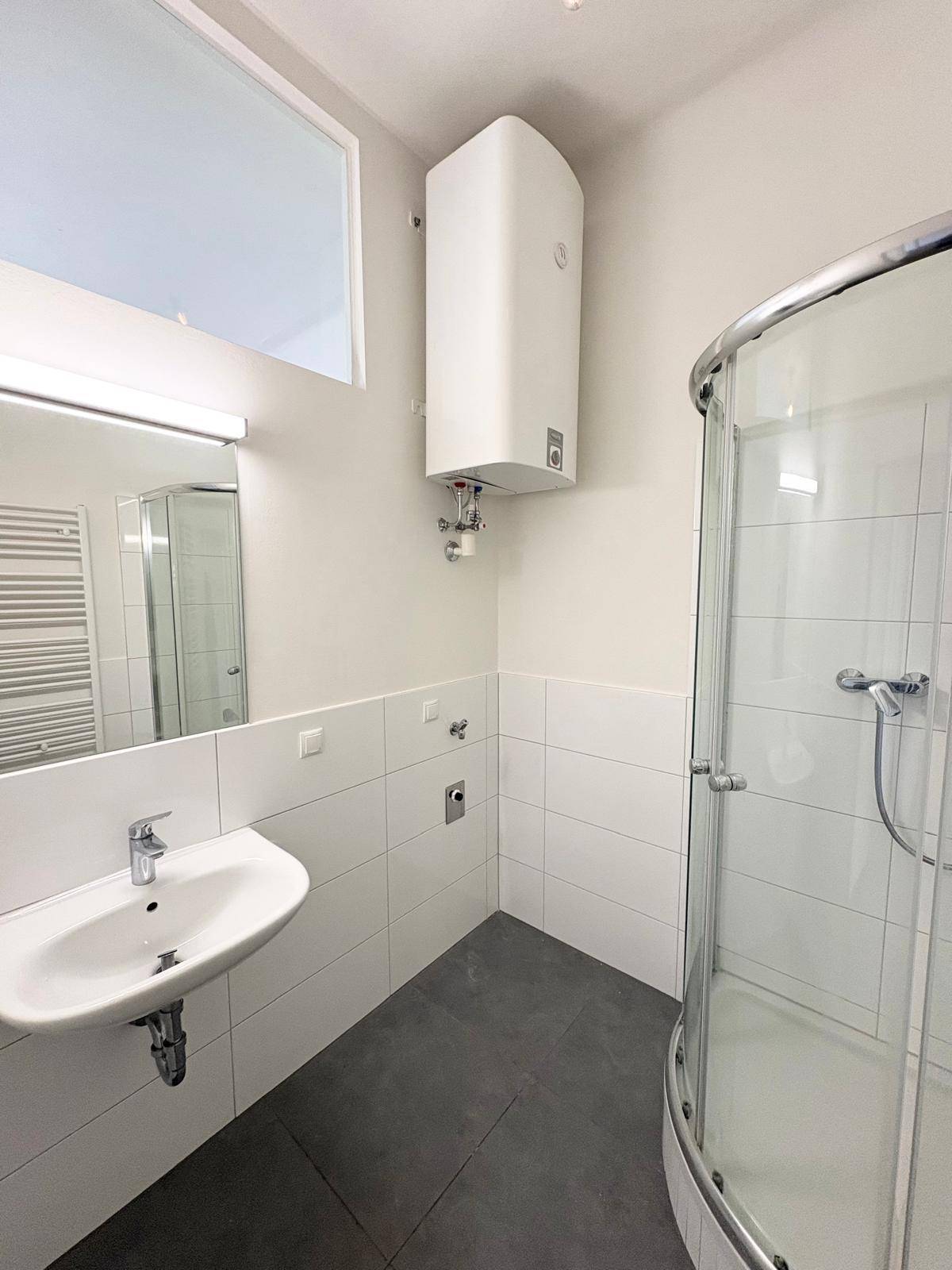 Funktionales Badezimmer mit Eckdusche, Einzelwaschbecken und praktischem Handtuchheizkörper.