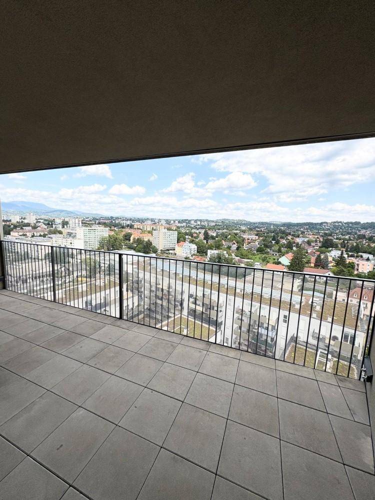 Weitläufige Terrasse mit Panoramablick auf die Stadt und die umliegende Landschaft unter blauem Himmel.