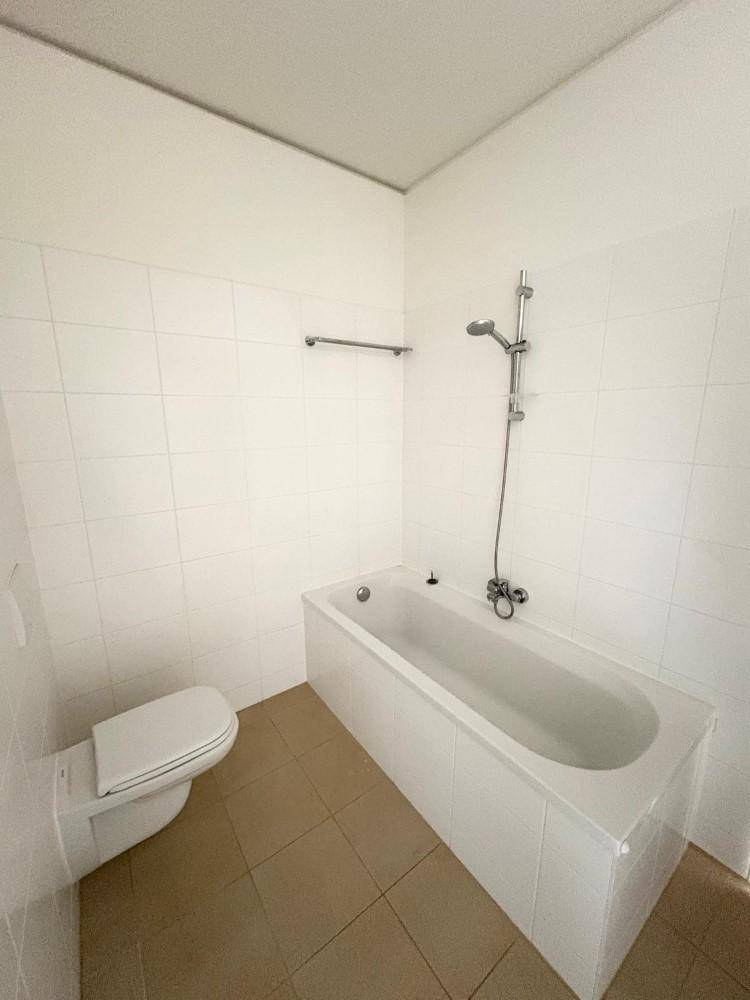 Badezimmer mit Badewanne, Toilette und hellen Fliesen, ideal für entspannende Momente.