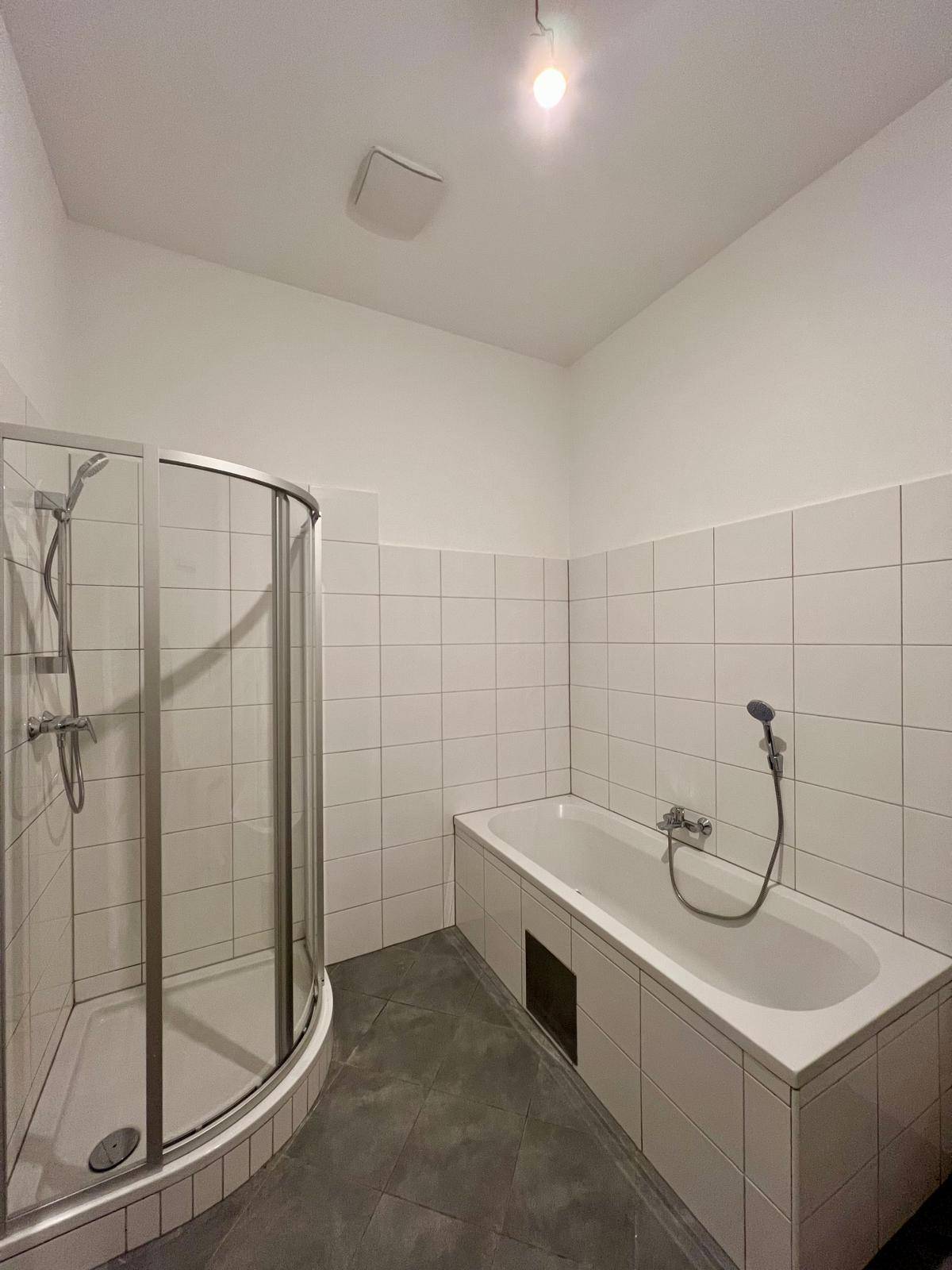 Badezimmer mit Badewanne, Duschkabine und weißen Fliesen an den Wänden.