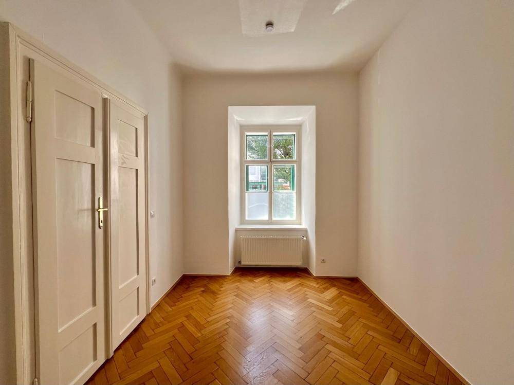 Gemütliches Zimmer mit Fischgrätparkett, Einbauschränken und einem Fenster.