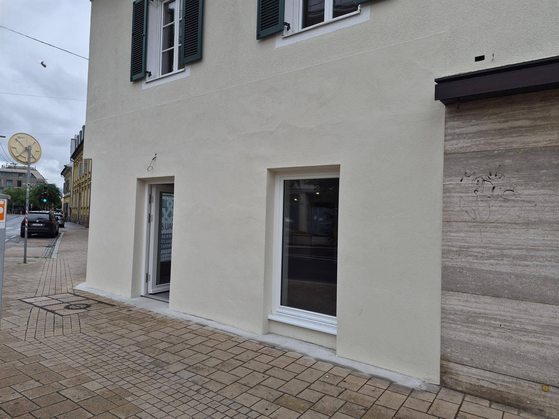 Außenansicht eines Geschäftsgebäudes mit heller Fassade und Fenstern zur Straße.