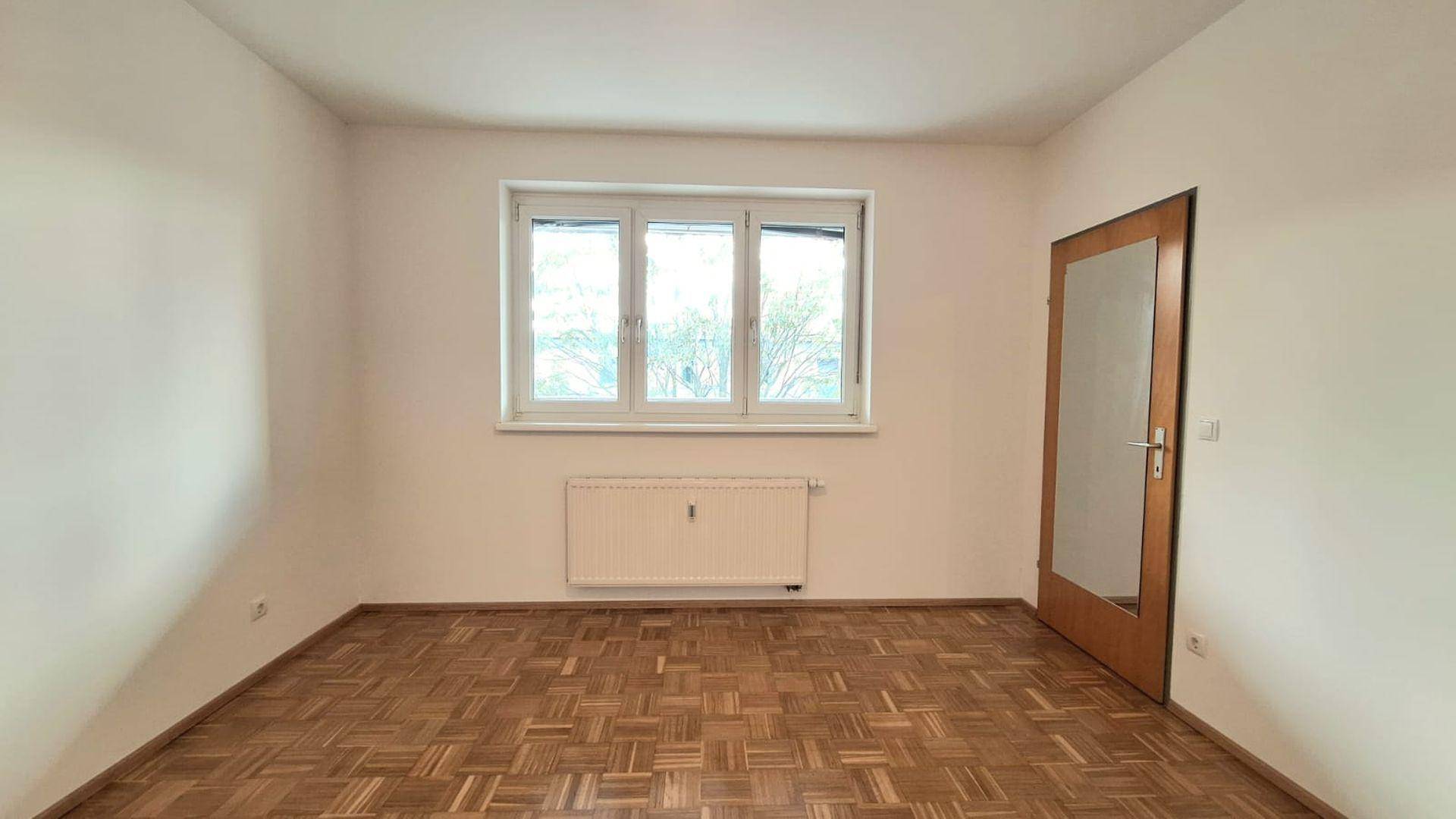 Gemütliches Zimmer mit Parkettboden und Fenster, ideal als Schlaf- oder Arbeitszimmer.