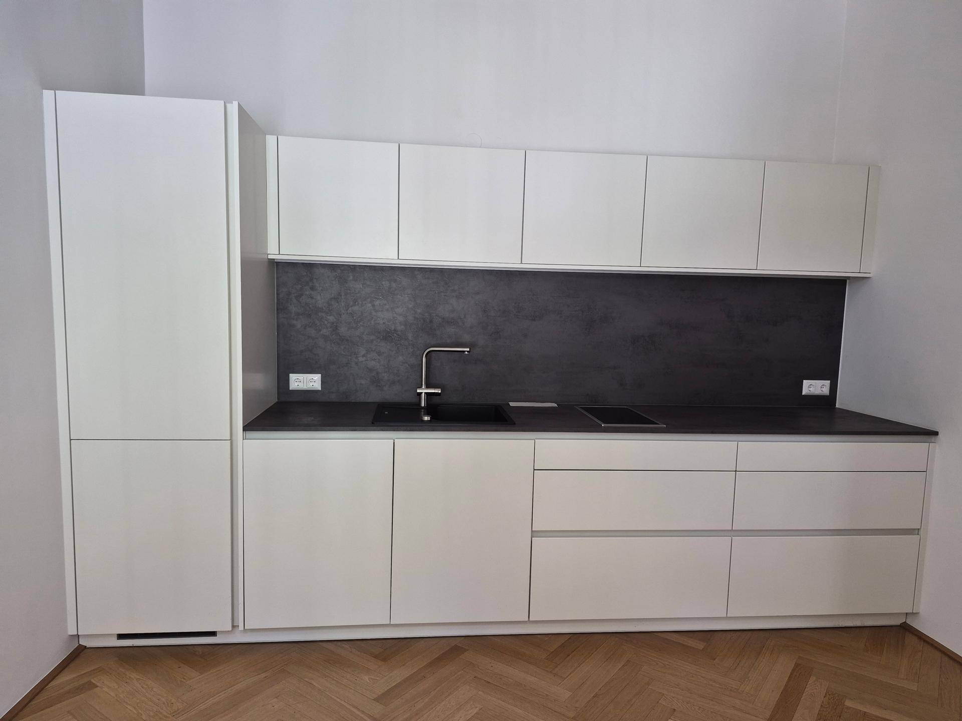 Moderne Einbauküche in Weiß mit dunkler Arbeitsplatte und integrierten Geräten.