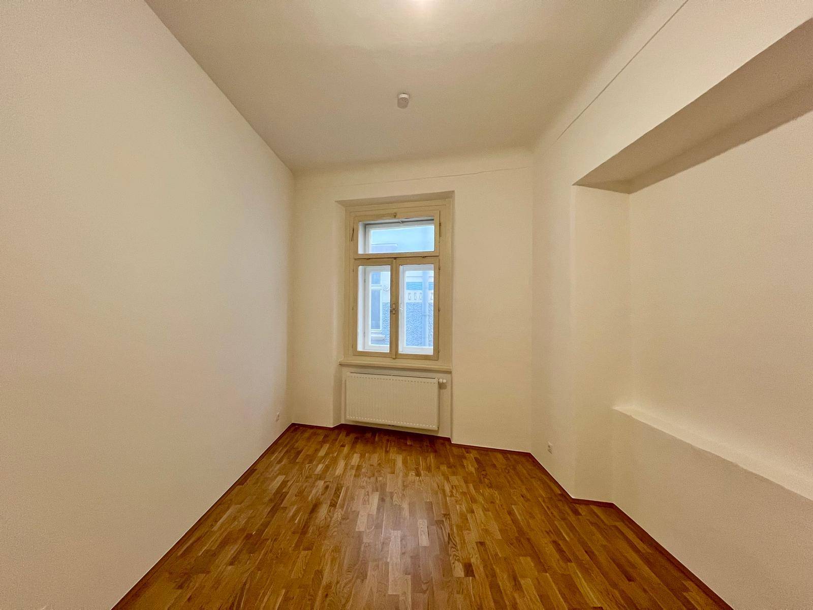 Kleines, helles Zimmer mit Parkettboden und einem Fenster, ideal als Schlaf- oder Arbeitszimmer.