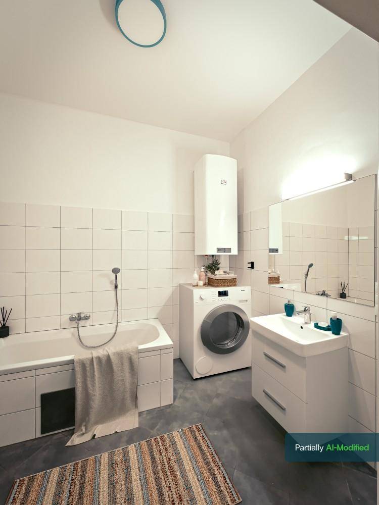 Modernes Badezimmer mit Badewanne, Waschmaschine, Fliesenboden und weißer Einrichtung.