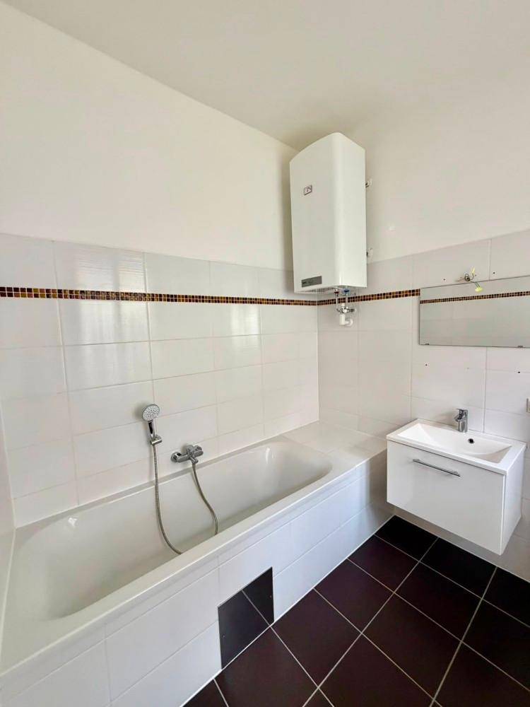 Badezimmer mit Badewanne, Waschbecken und Wandfliesen in Weiß und Braun.