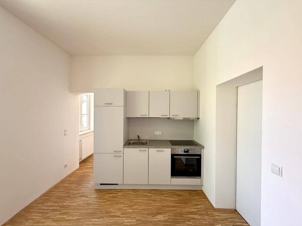 Helle Küchenzeile mit weißen Schränken und integrierten Geräten in einem modernen Raum.