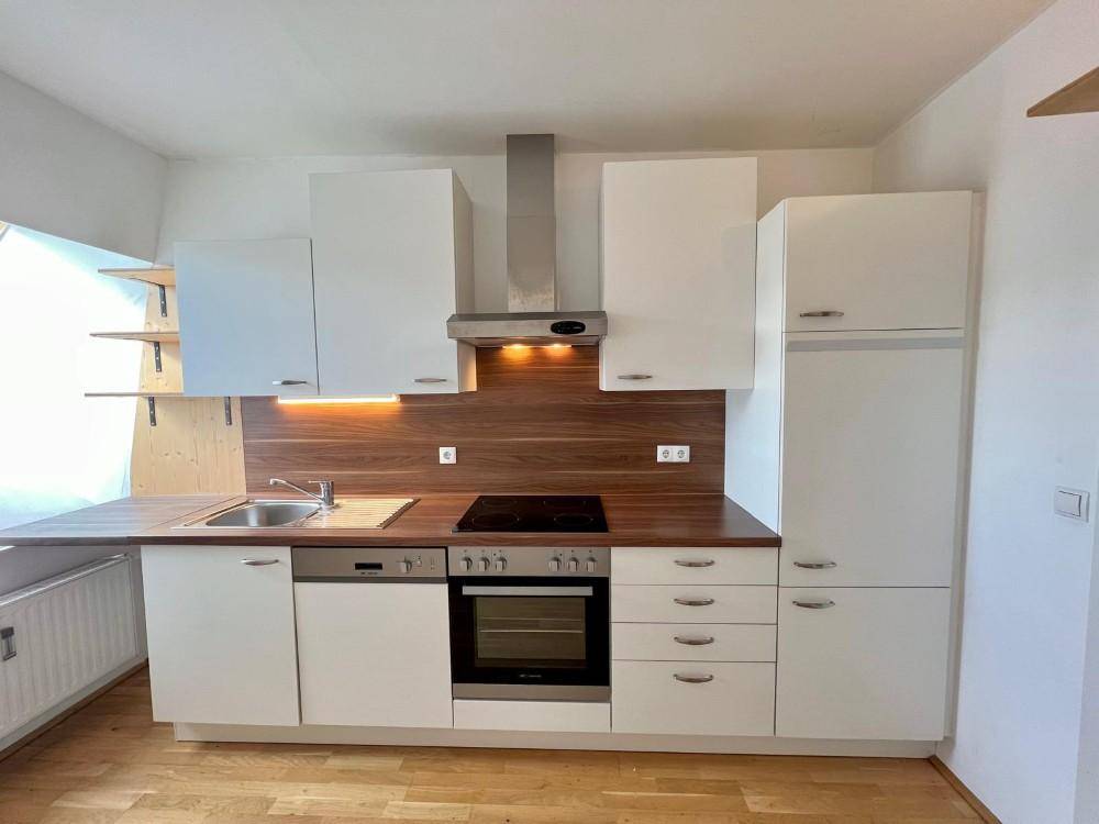 Moderne Einbauküche mit weißen Schränken, Holz-Arbeitsplatte und integrierten Geräten.