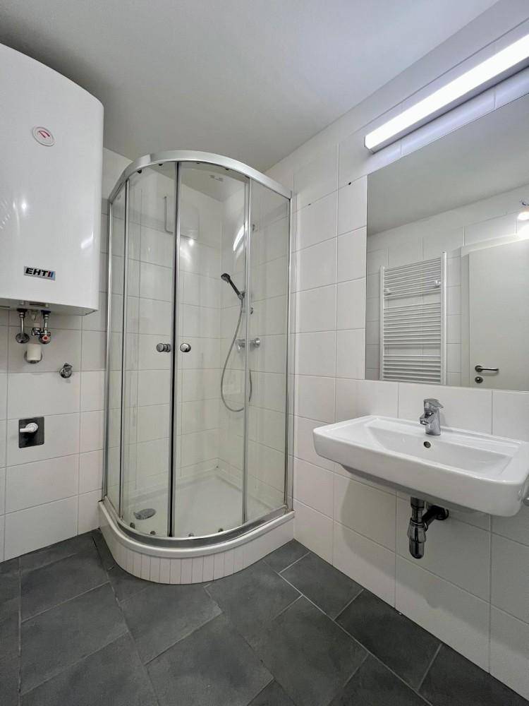 Modernes Badezimmer mit Duschkabine, Waschbecken und weiß gefliesten Wänden.