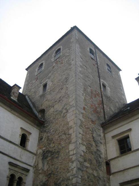 Massiver Steinturm mit kleinen Fenstern, der Teil der historischen Architektur des Anwesens ist.