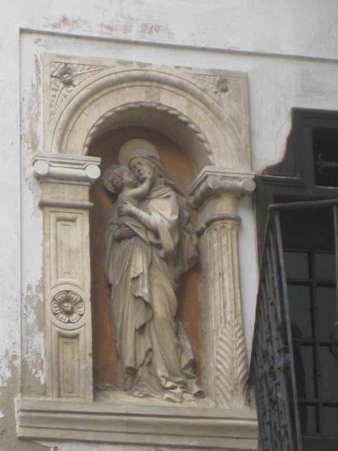 Antike Marienstatue mit Kind in einer verzierten Nische an der Außenwand des historischen Gebäudes.