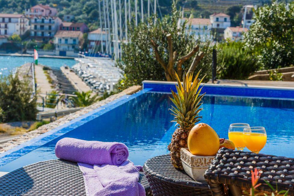 Erfrischender Poolbereich mit tropischen Früchten und Blick auf den Hafen und das azurblaue Meer.