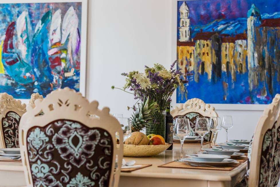 Eleganter Essbereich mit kunstvollen Stühlen, gedecktem Tisch und farbenfrohen Gemälden an der Wand.