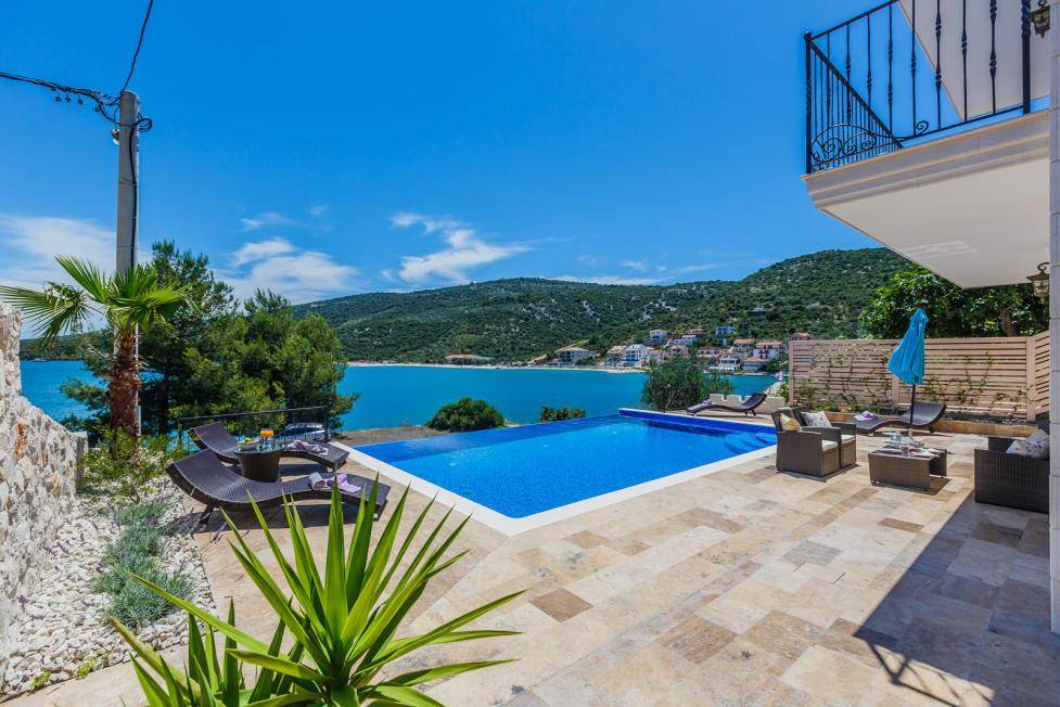 Exklusiver Außenbereich mit großem Pool, Sonnenterrasse und Panoramablick auf die Bucht und die Umgebung.